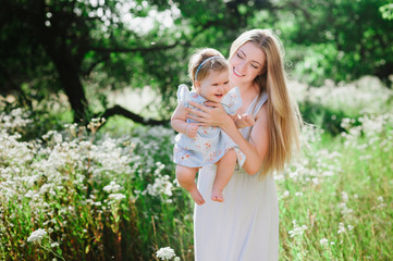 young mother playing with her little daughter on the nature, motherhood, tenderness, childhood, tend