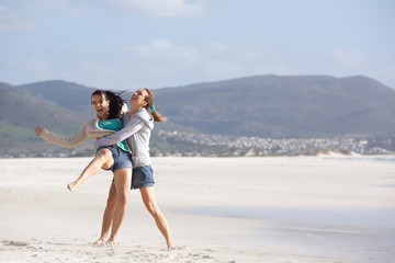 Wall Mural - Two playful girlfriends having a good time at the beach