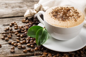 Close-up of coffee cup with roasted coffee beans on wooden backg