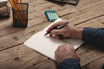 businessman writing to notebook on a wooden table