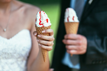 bride and groom holding icecream in their hands on wedding day