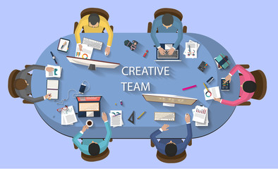 Flat design - business concept - top view of creative team working together around a desk with a desktop, laptop, tablet and other objects , trying to find new and bright ideas for the company.