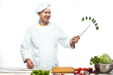 Chef cutting a green cucumber in his kitchen