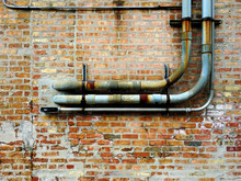 Rusted Pipes Against Brick Wall