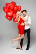 Happy beautiful couple posing on grey background and holding bal