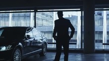 Businessman In A Suit Is Walking Towards An Executive Car In A Garage Parking Lot. Shot On RED Cinema Camera.