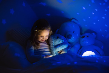 Wall Mural - Little girl reading a book in bed