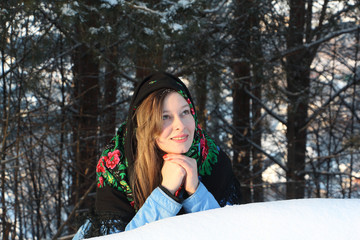 Wall Mural - The woman with long hair in an elegant scarf against a snowdrift