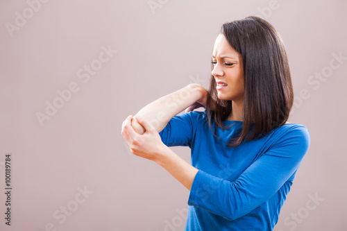 Fotografía Portrait of young woman who is having pain in her elbow.
