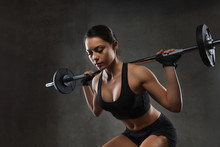 Young Woman Flexing Muscles With Barbell In Gym