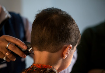 two year old kid having a haircut  with wet eyes after crying early morning with golden light falling on his face