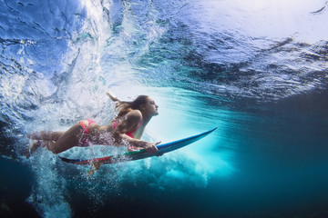 young girl in bikini - surfer with surf board dive underwater with fun under big ocean wave. family 