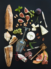 Poster - Wine and snack set. Baguette, glass of white, figs, grapes, nuts, cheese variety, meat appetizers, herbs on black grunge background, top view.