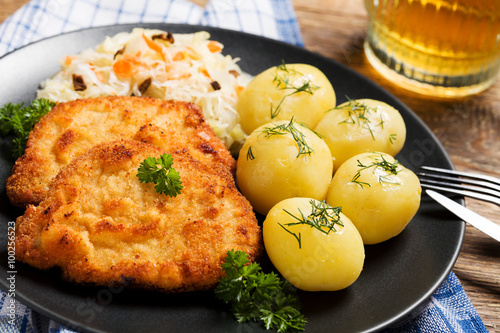 Fototapeta na szkło Smażony kotlet schabowy w bułce tartej, podawany z gotowanymi ziemniakami i