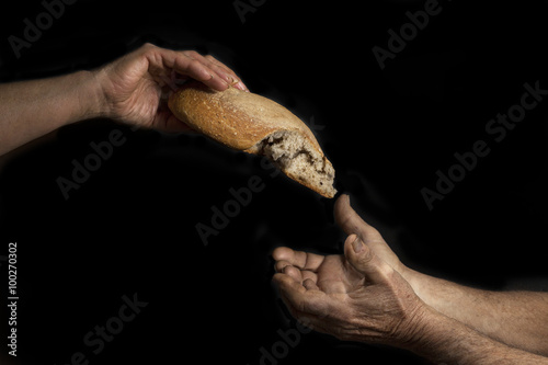 Fotografía Mano di donna dona pagnotta di pane a un povero senzatetto