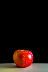 Red apple an a wooden board with black background