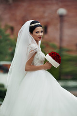 Beautiful brunette bride in white dress with a rose bouquet posi