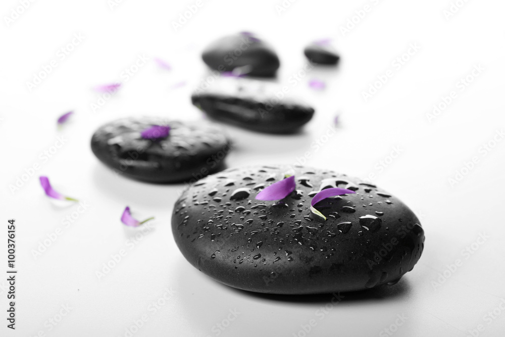 Hot spa stones with flower petals, isolated on white