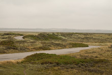 The Road Through. A Road Winds Its Way Through The Coastal Terrain Of Denmark.