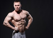 © chettythomas - Strong muscular man posing in studio over dark background