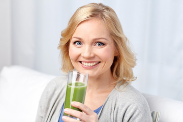 happy woman drinking green juice or shake at home