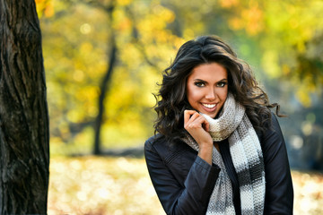 Wall Mural - Portrait of smiling woman wearing leather jacket and scarf. Young woman in beautiful autumn park, concept autumn.