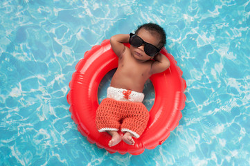 newborn baby boy floating on a swim ring