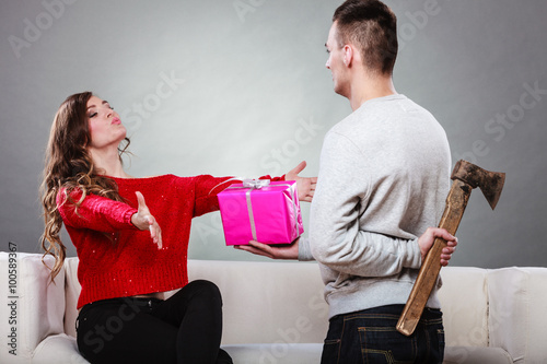 Fotografie, Obraz Insincire man holding axe giving gift box to woman