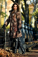 Wall Mural - Autumn girl in elegant coat posing with colorful fall leaves in beautiful yellow park foliage.