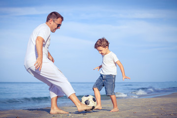 Wall Mural - Father and son playing on the beach at the day time.