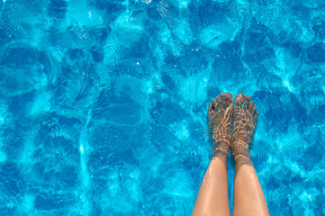 Female legs in the pool water in summer