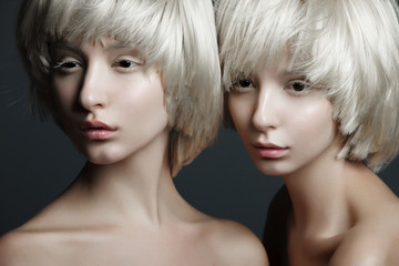 Portrait of two beautiful girls twins with closed eyes in studio, closeup