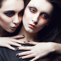 Portrait of two beautiful young girls twins in the studio on a black background, the concept of health and beauty