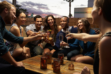 Group Of Friends Enjoying Night Out At Rooftop Bar