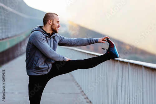 Cuadros en Lienzo Athletic runner doing stretching exercise, preparing for morning