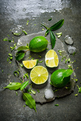 Wall Mural - Lime background. Slices of lime with ice and leaves on a stone stand .