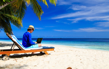 man with laptop on tropical beach