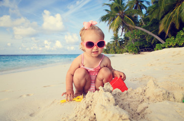 cute little girl playing with sand on beach