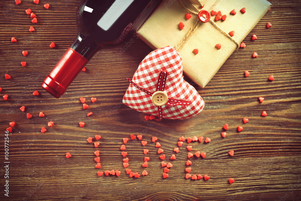 Red wine bottle and gift box on wooden background