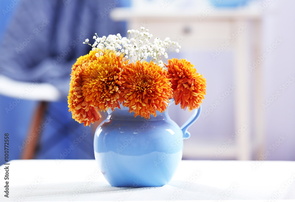 Vase of orange chrysanthemums on table