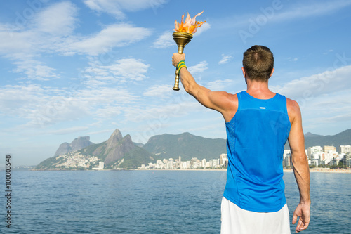 Fotografía Athlete in athletic uniform standing with sport torch in front of Rio de Janeiro