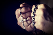  Caucasian person's hands tighten a Christian rosary for prayer. concept of religious belief and faith.
