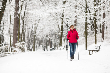 Nordic walking - middle-age woman working out in city park 