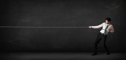 Businessman pulling rope on grey background