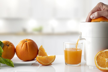 Hand squeezing an orange on a kitchen table horizontal compositi