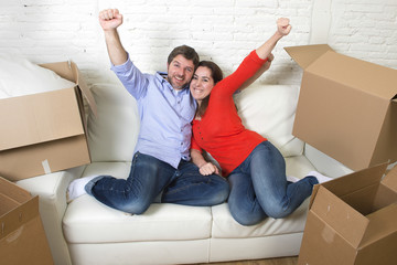  young happy American couple lying on couch together celebrating moving to new house unpacking cardboard boxes