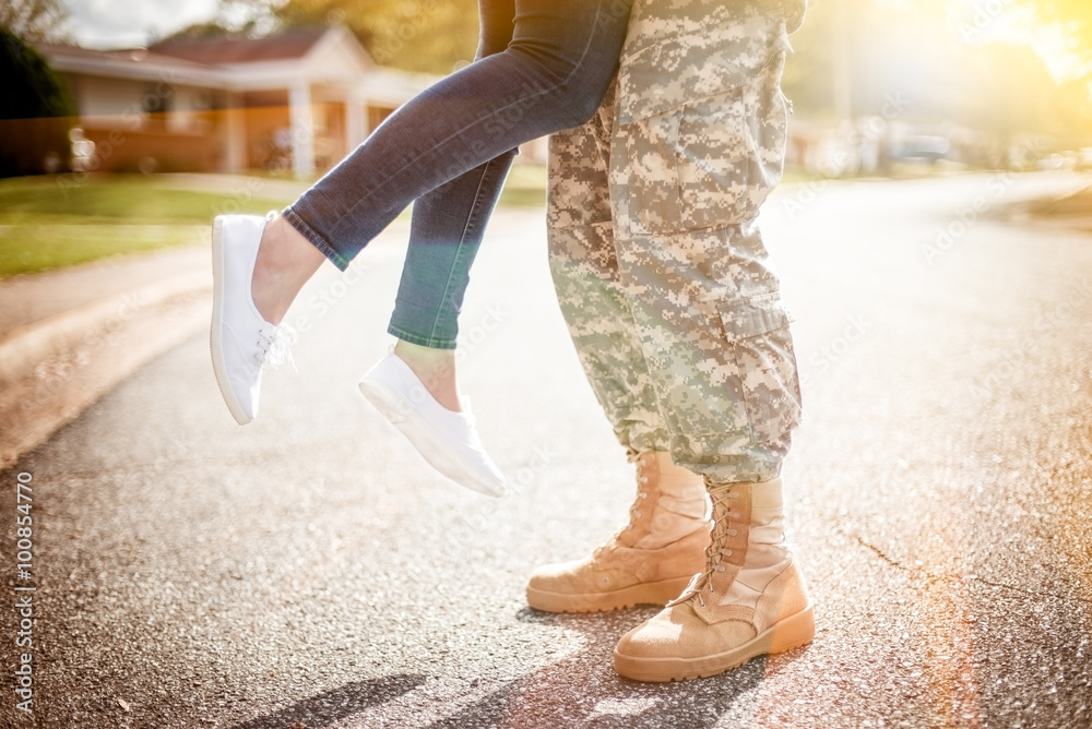 Young military couple kissing each other, homecoming concept, wa - obrazy, fototapety, plakaty 