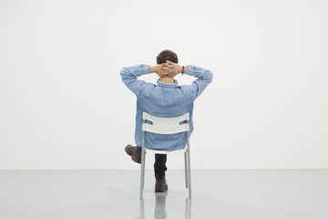 Wall Mural - Man sitting on a chair in white room