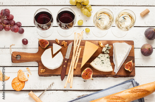 Cuadros en Lienzo Red and white wine plus different kinds of cheeses (cheeseboard) on rustic wooden table