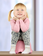 Small  smily girl sits  on a potty